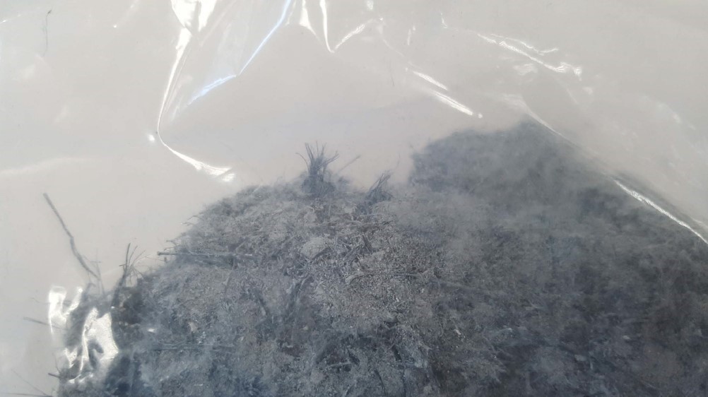 A la imatge veiem una mostra de fibres blavoses d'amiant, possiblement crocidolita, dins una bossa.